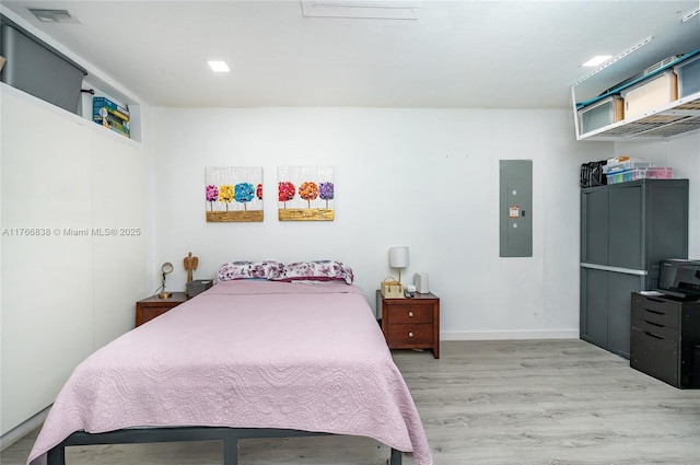 bedroom featuring electric panel, visible vents, baseboards, and wood finished floors