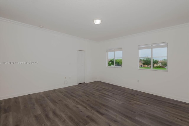 spare room featuring baseboards, ornamental molding, and dark wood finished floors