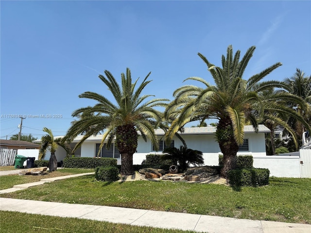 9545 SW 181st Ter, Palmetto Bay, FL 33157 - obstructed view of property with stucco siding, a front lawn, and fence