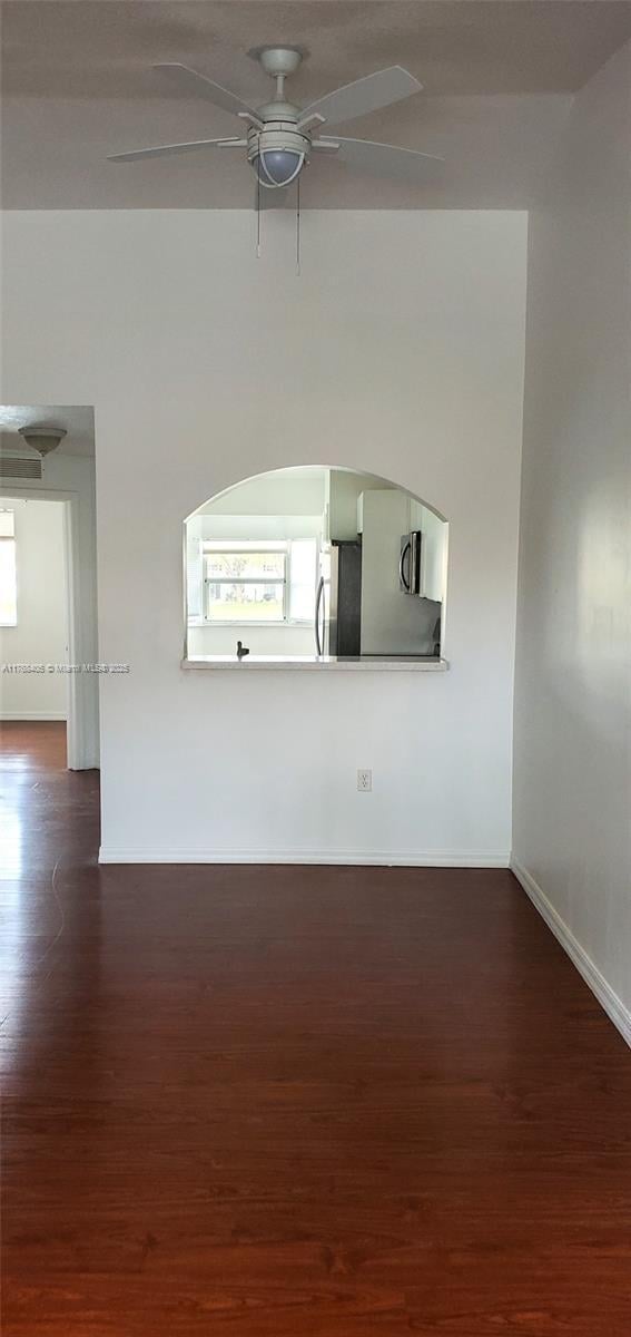 spare room featuring dark wood-type flooring, baseboards, and ceiling fan