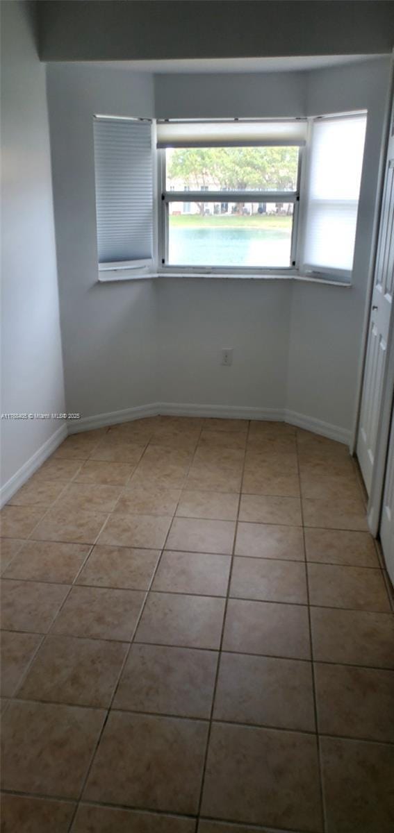 tiled empty room featuring baseboards and plenty of natural light