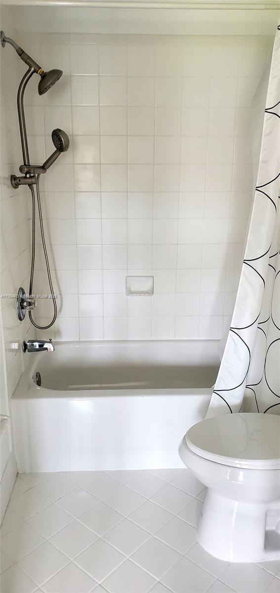 full bath featuring tile patterned flooring, toilet, and shower / bath combo with shower curtain
