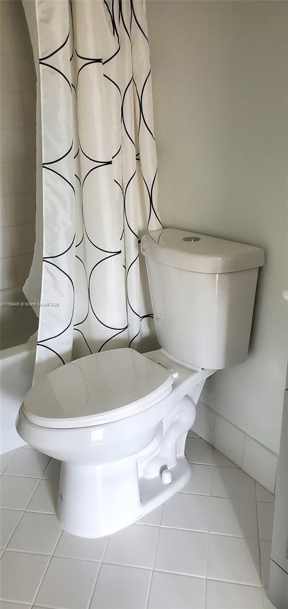 full bathroom with tile patterned flooring, toilet, and a shower with shower curtain