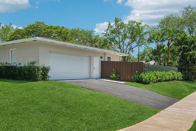 7640 SW 165th Ter, Palmetto Bay, FL 33157 - exterior space with fence, an attached garage, a lawn, stucco siding, and driveway