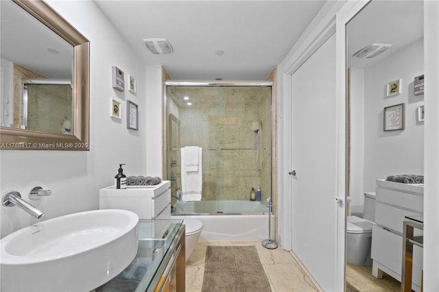 bathroom with toilet, vanity, visible vents, and bath / shower combo with glass door