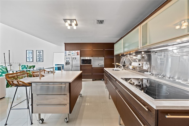 kitchen with light countertops, a kitchen island with sink, visible vents, modern cabinets, and stainless steel appliances