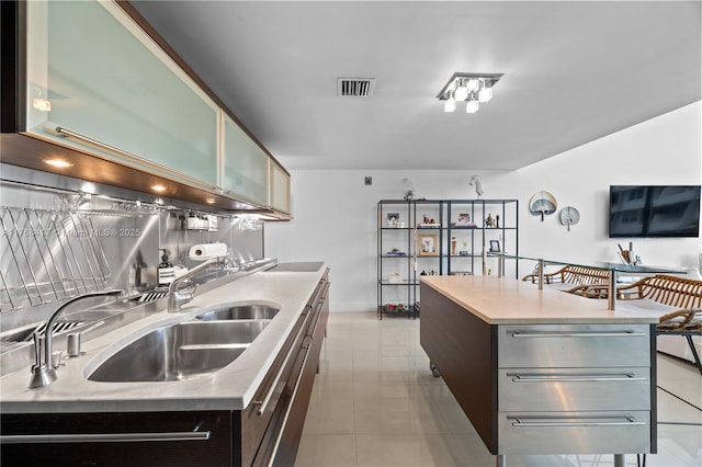 kitchen with modern cabinets, visible vents, a kitchen island, light countertops, and a sink
