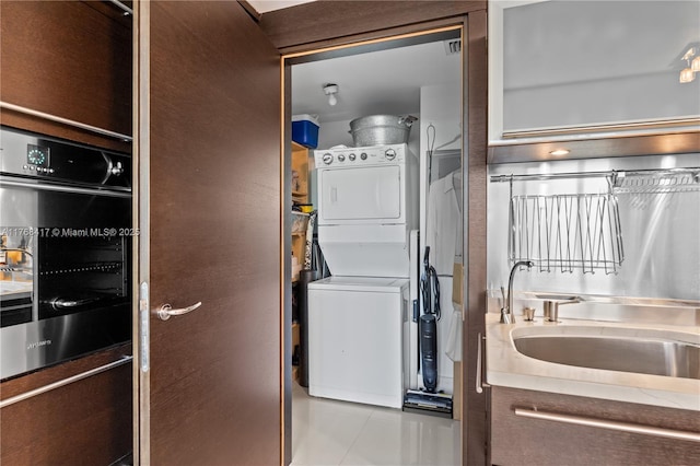 washroom featuring tile patterned flooring, stacked washer / drying machine, and laundry area
