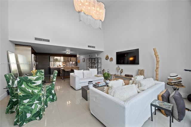 living room with baseboards, light tile patterned floors, a towering ceiling, and visible vents