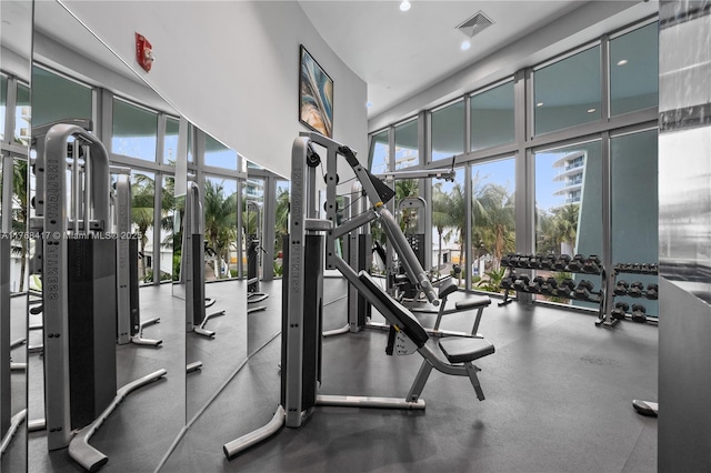 workout area with a high ceiling, recessed lighting, visible vents, and expansive windows