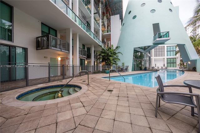 pool with fence, a patio area, and a community hot tub