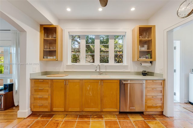 kitchen with glass insert cabinets, a sink, light countertops, and stainless steel dishwasher