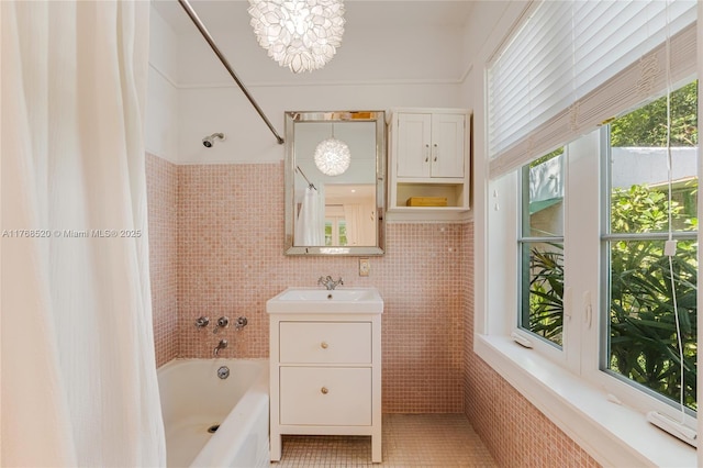 full bathroom with a notable chandelier, vanity, tile walls, and shower / bath combo