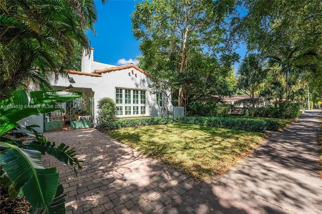 back of property featuring stucco siding, a lawn, and a tile roof