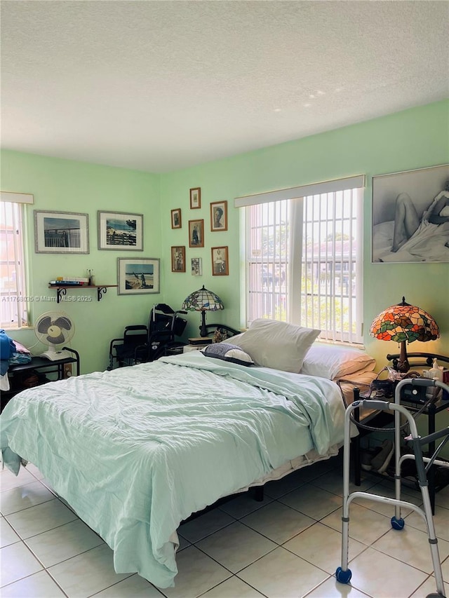 bedroom featuring light tile patterned floors, multiple windows, and a textured ceiling