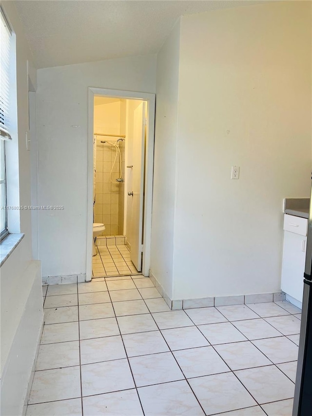 hallway featuring light tile patterned floors and baseboards