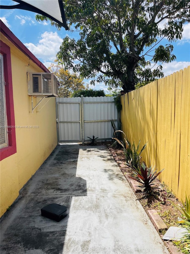 view of patio featuring an AC wall unit, a gate, and fence