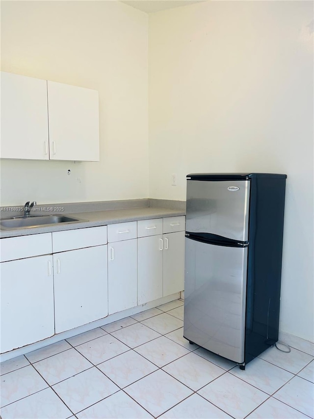 kitchen with white cabinetry, freestanding refrigerator, light countertops, and a sink