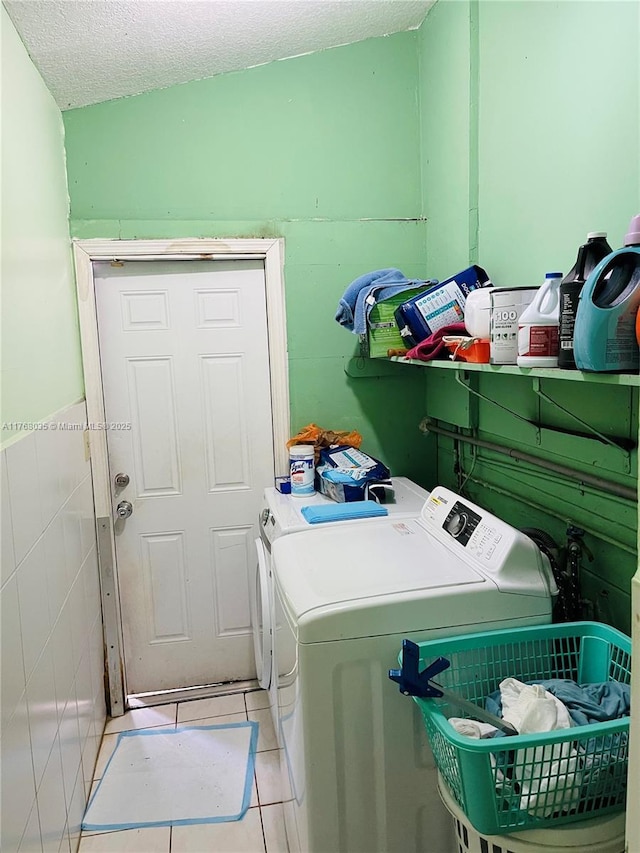 washroom with washer and dryer, a textured ceiling, light tile patterned flooring, and laundry area