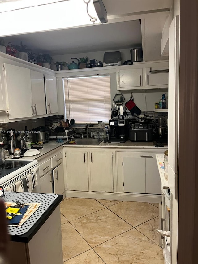 8101 N Sunrise Lakes Dr Unit 105, Sunrise, FL 33322 - kitchen featuring a sink, decorative backsplash, light tile patterned floors, white electric range, and white cabinets