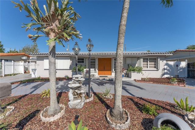 view of front of home with a gate, stucco siding, and fence
