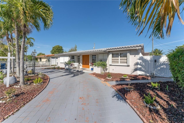 view of front facade with stucco siding, driveway, fence, and a gate