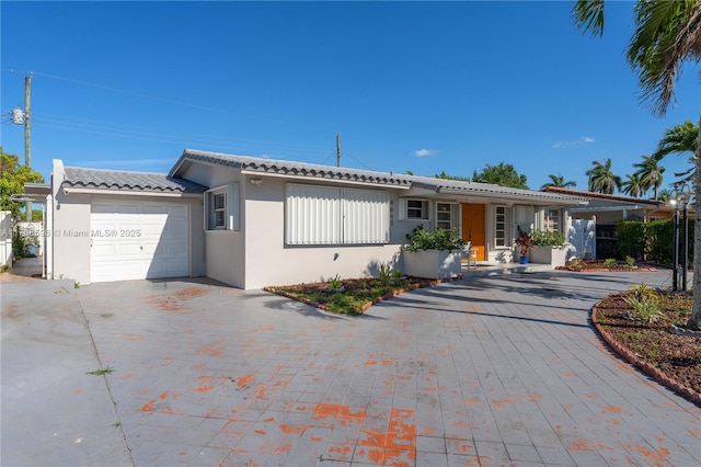 ranch-style home with a tiled roof, a garage, driveway, and stucco siding