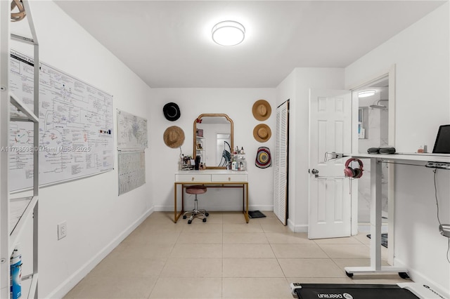 exercise room featuring light tile patterned flooring and baseboards