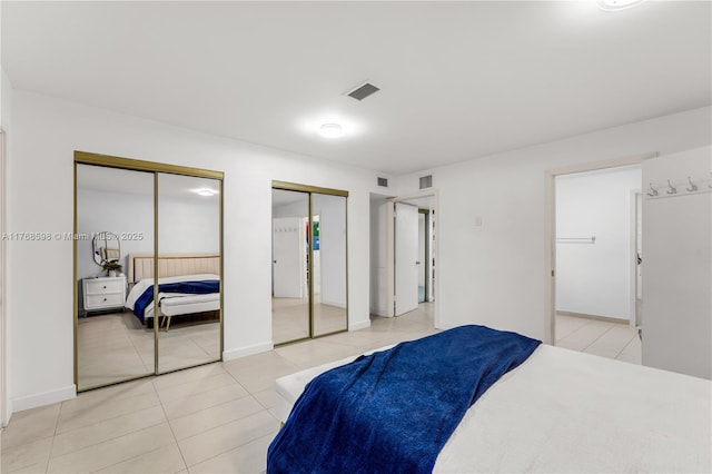 bedroom featuring visible vents, two closets, and light tile patterned flooring