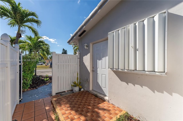 view of exterior entry with a patio, fence, and stucco siding