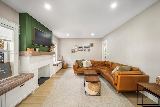 living area with a fireplace, light wood-style flooring, and recessed lighting