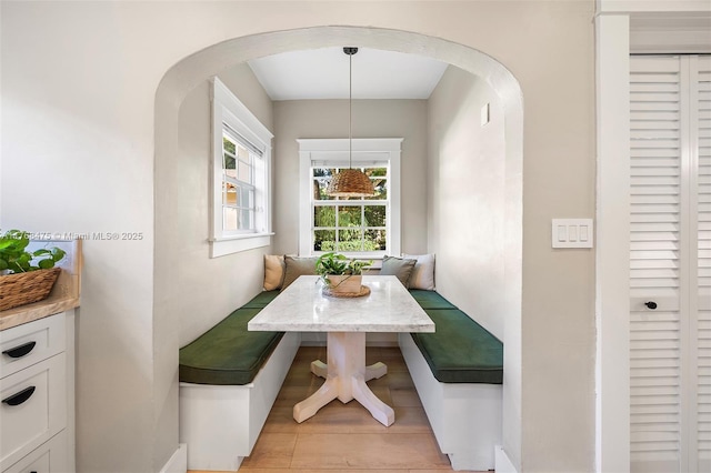 dining space featuring light wood-type flooring, arched walkways, and breakfast area