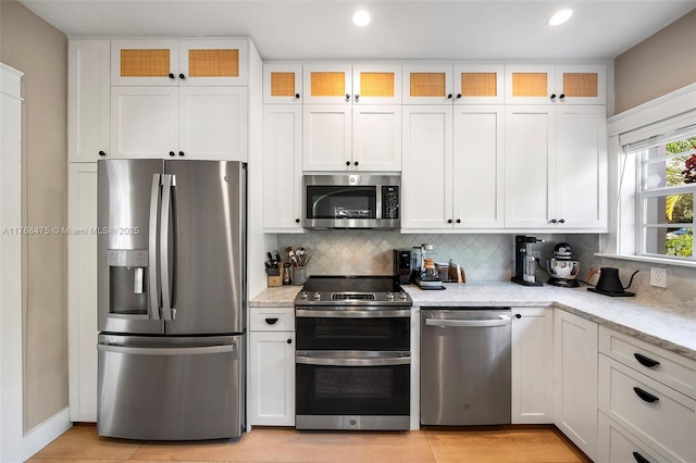 kitchen featuring white cabinetry, tasteful backsplash, appliances with stainless steel finishes, and light stone counters