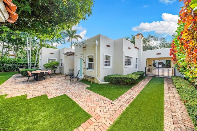 rear view of property with a chimney, stucco siding, fence, a patio, and a yard