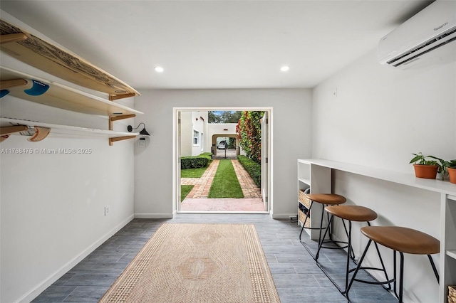 interior space with an AC wall unit, baseboards, and wood finished floors