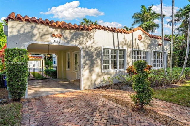 view of home's exterior with stucco siding, a tile roof, fence, and a carport