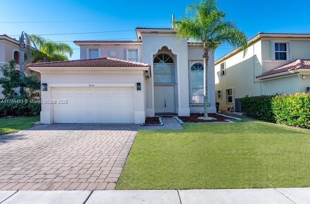 mediterranean / spanish house featuring stucco siding, a front lawn, a garage, a tile roof, and decorative driveway