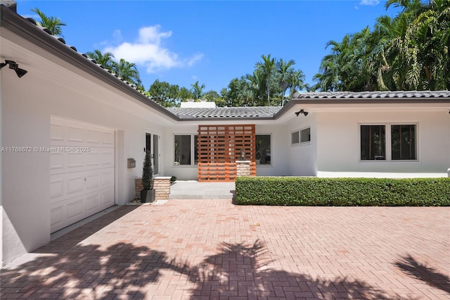 1221 NE 87th St, Miami, FL 33138 - exterior space featuring stucco siding, an attached garage, decorative driveway, and a tile roof