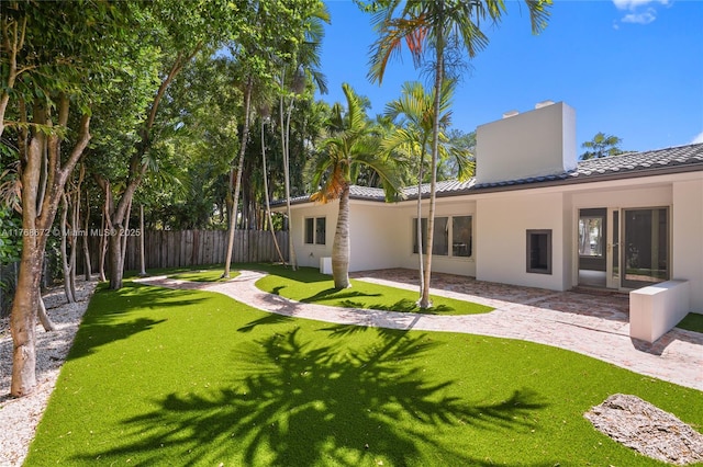 1221 NE 87th St, Miami, FL 33138 - rear view of house featuring a chimney, a tile roof, a lawn, fence, and stucco siding