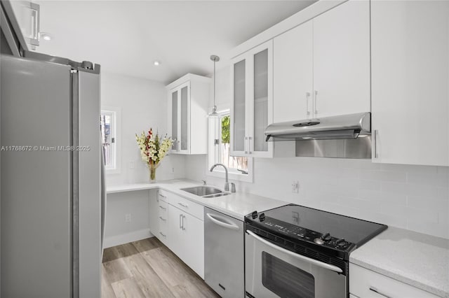 1221 NE 87th St, Miami, FL 33138 - kitchen with white cabinets, a sink, light wood-style floors, stainless steel appliances, and under cabinet range hood