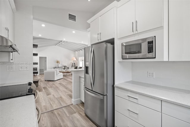 1221 NE 87th St, Miami, FL 33138 - kitchen featuring white cabinets, light wood finished floors, stainless steel appliances, lofted ceiling, and visible vents