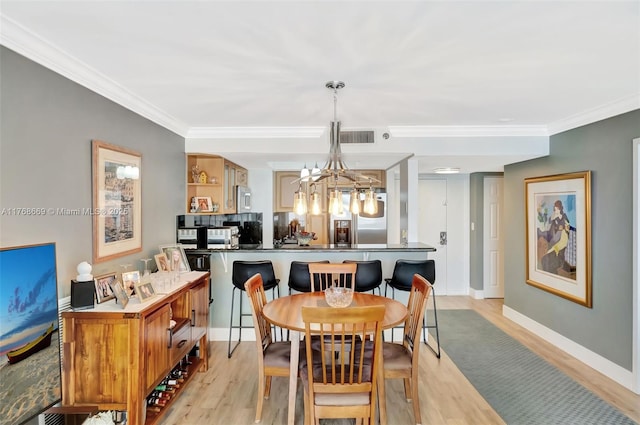 dining space featuring baseboards, ornamental molding, light wood-style flooring, and a notable chandelier