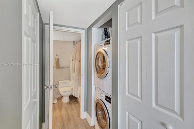 laundry area with light wood-style floors, stacked washer / drying machine, and laundry area