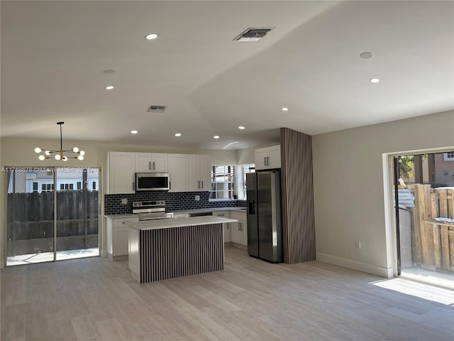 kitchen with white cabinetry, a center island, stainless steel appliances, a chandelier, and visible vents