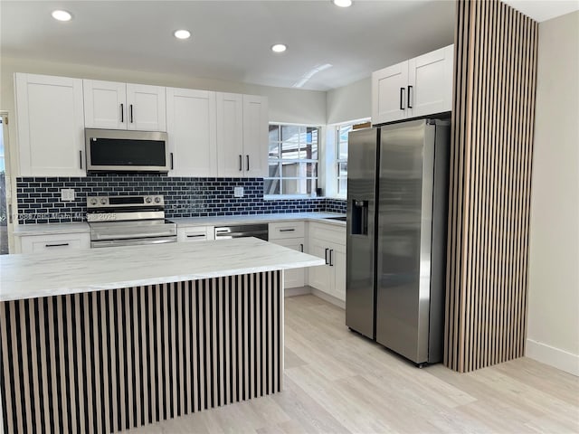 kitchen with white cabinetry, light wood-style floors, backsplash, and stainless steel appliances