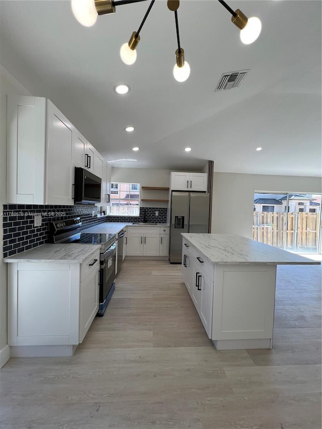 kitchen with white cabinetry, tasteful backsplash, stainless steel appliances, a center island, and visible vents