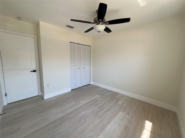 unfurnished bedroom with a closet, a ceiling fan, light wood-type flooring, baseboards, and visible vents