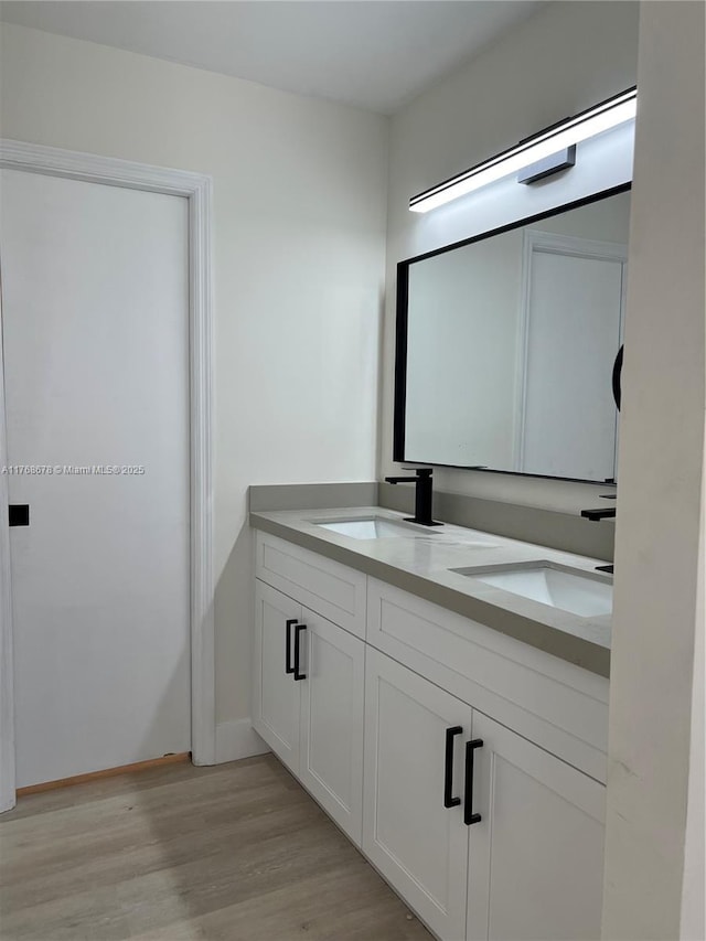 full bath with double vanity, a sink, and wood finished floors