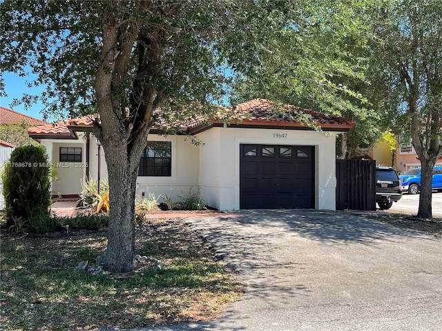 view of front facade featuring a tiled roof, stucco siding, driveway, and a garage