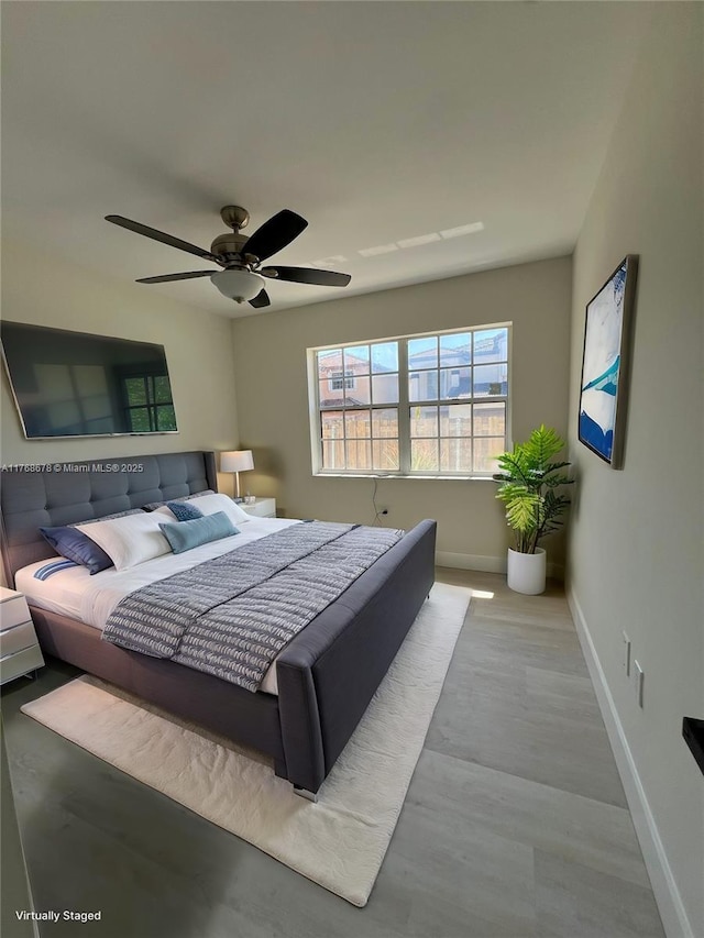 bedroom with baseboards, wood finished floors, and a ceiling fan